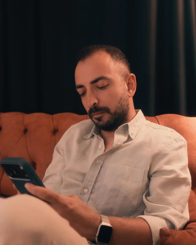 Aytaç Bayladı seated on a leather sofa